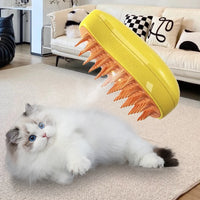 Thumbnail for A fluffy white cat on a rug looks up at a floating KittyNook Cat Co. Electric Cat Grooming Brush with orange bristles.