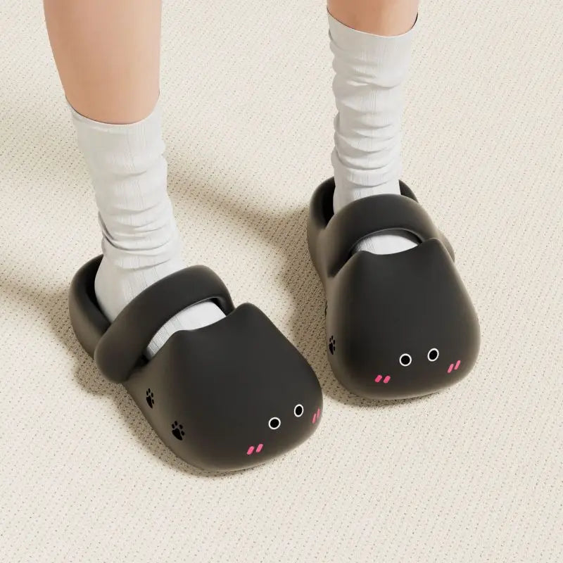 A person stands on a light-textured floor wearing KittyNook Cat Co.'s Adorable Cat Face Comfort Sandals and white socks.