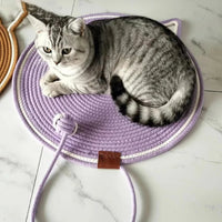 Thumbnail for Gray tabby cat on a KittyNook Cat Co. Tails Cat Scratching Mat, a round purple, cat-shaped mat with an attached tail design.