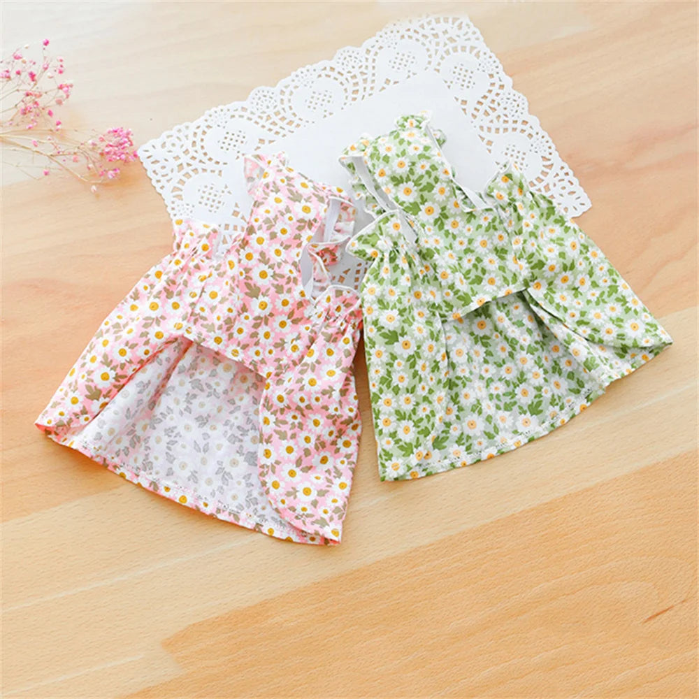 Two KittyNook Cat Co. Summer Cotton Cat Dresses in pink and green shown on wood with a white doily backdrop.