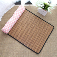Thumbnail for The Natural Rattan Cat Sleeping Mat by KittyNook Cat Co. features a black border and pink-checkered fabric, beside a plant.