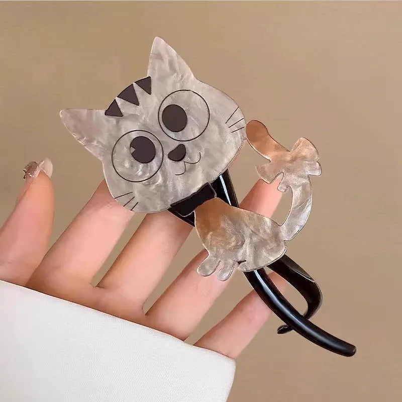 A hand holds The Acrylic Cat Hairpin by KittyNook Cat Co.—a cute cat lover gift with big eyes and a curly tail.