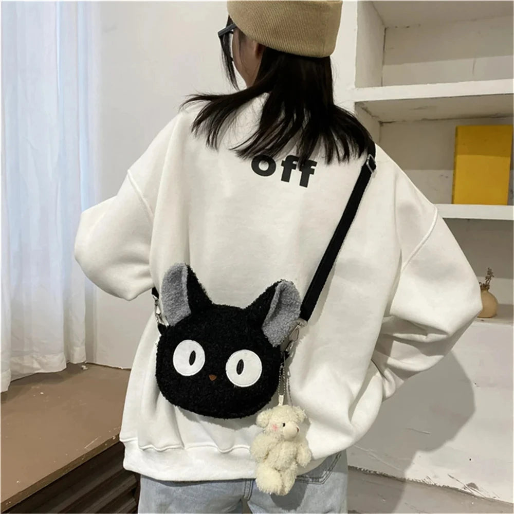 A woman wearing a white sweatshirt with a KittyNook Cat Co. Neko Soft Cat Shoulder Bag shaped like an anime cat.