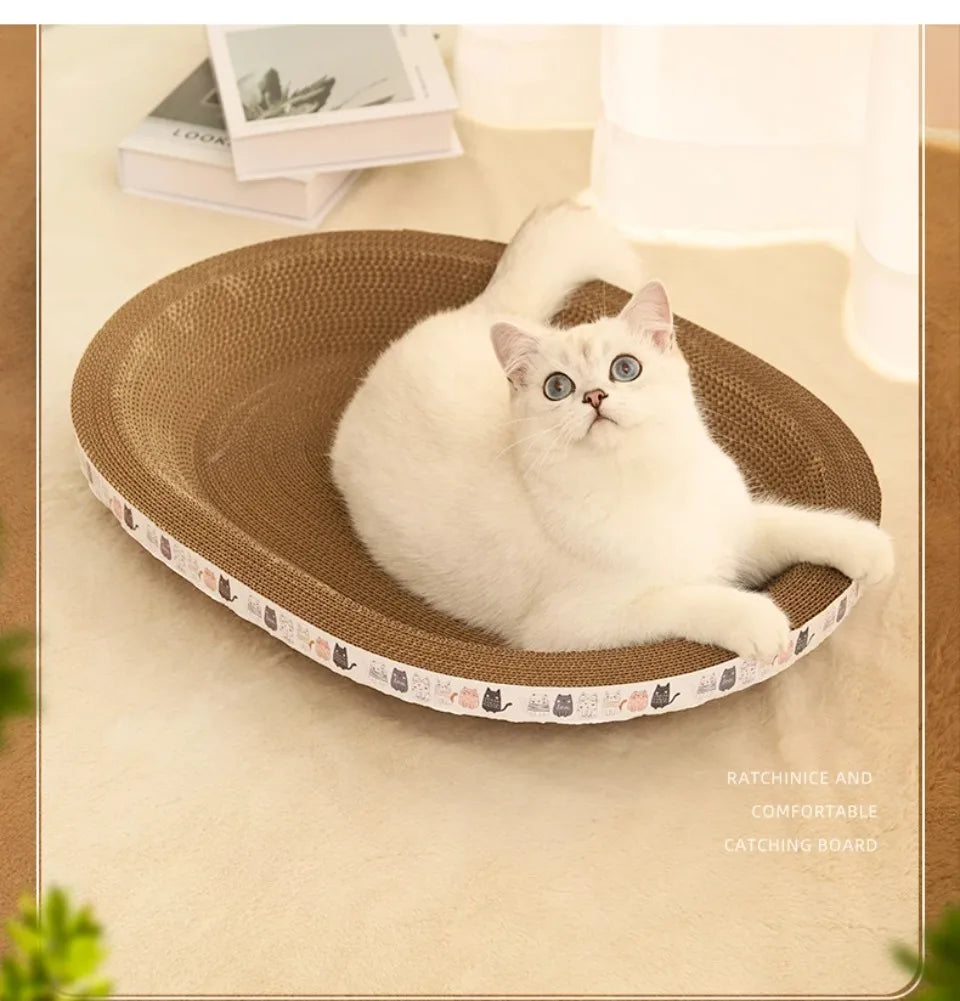 White cat in KittyNook Cat Co. Oval Corrugated Cat Scratching Board on carpet, books in background.