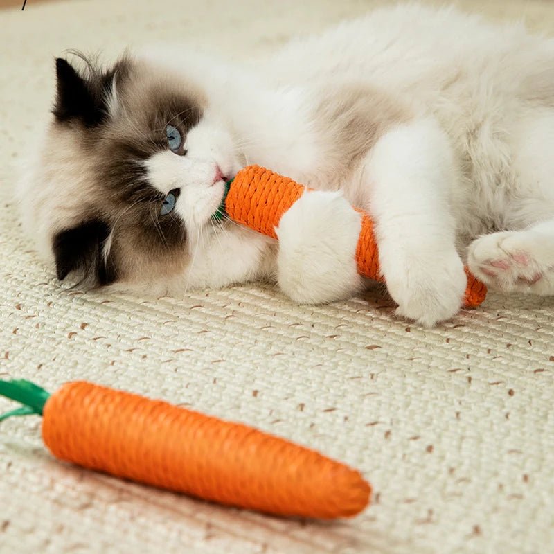 Fluffy cat on a rug bites a KittyNook Cat Co. Bite-Resistant Cat Toy carrot, with another toy carrot nearby.
