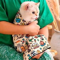 Thumbnail for Someone in green holds a cat in a KittyNook Cat Burrito Grooming Wrap—anti-bite, anti-scratch, easy nail trimming.