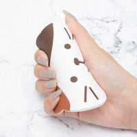 Thumbnail for A hand holds a white cat squishy toy next to a KittyNook Cat Co. Cat Silicone Cup Coaster Mat on marble.
