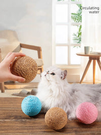 Thumbnail for A fluffy white cat eyes KittyNook Cat Co.'s Premium Sisal Kitten Scratching Ball and three colorful eco-friendly balls.