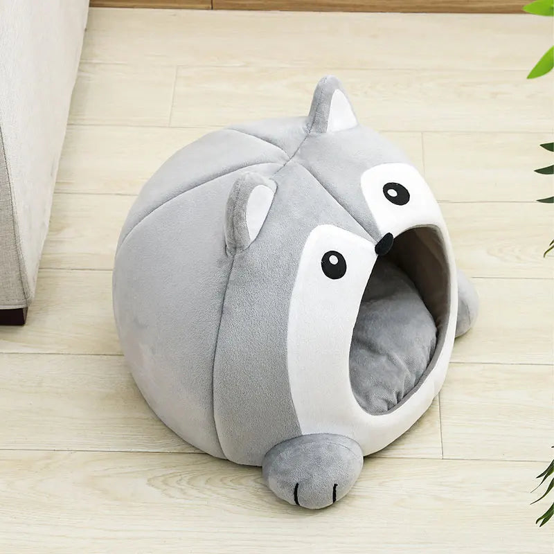 The KittyNook Cat Co. Fluffy Indoor Cat Cave Bed for Kittens, shaped like a cute animal, rests on a wooden floor.