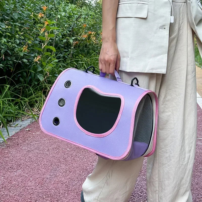 Person holding KittyNook Cat Co.'s Premium Foldable Small Cat Carrying Bag with pink trim on a red path near green plants.