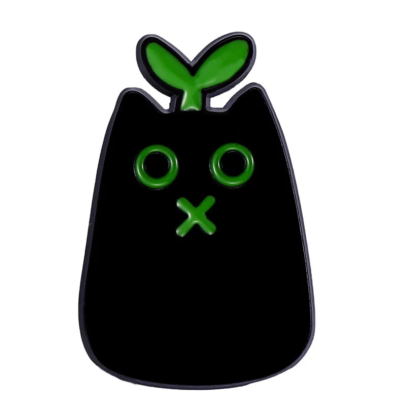 KittyNook Cat Co. Black Cat Enamel Brooch with green eyes, a green "X" mouth, and a sprout on its head.