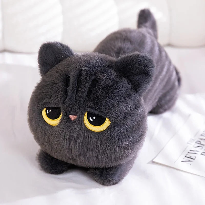 The Plush Cat Pillow: Whimsical Home Cozy by KittyNook Cat Co. features a gray cat with big yellow eyes by a newspaper.