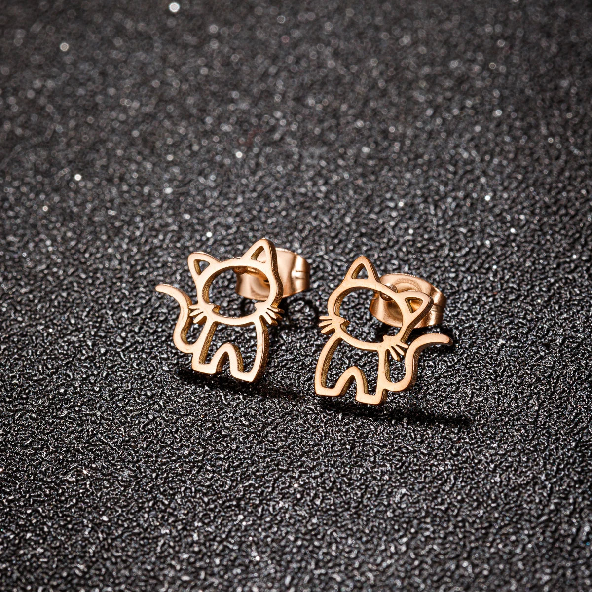 KittyNook Cat Co.’s KittyShine Stainless Steel Ear Studs gleam on a textured dark surface.