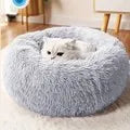 A fluffy white cat rests in the Warm & Soft Cat Sleeping Pod by KittyNook Cat Co. on a wooden floor indoors.