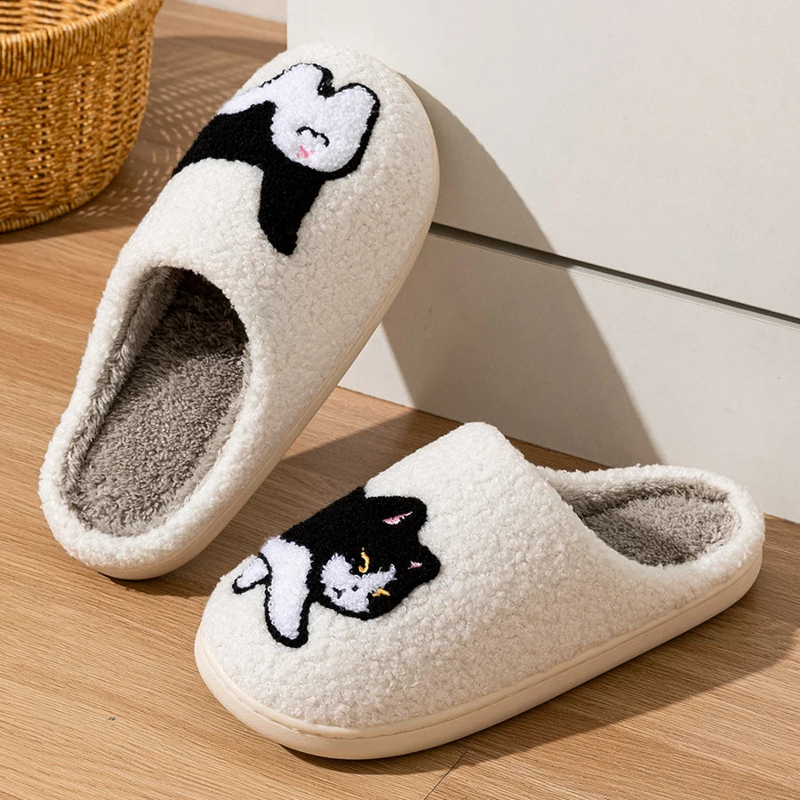 CozyPaws Cute Cat House Slippers by KittyNook Cat Co. with black and white cartoon cats rest on a wooden floor.