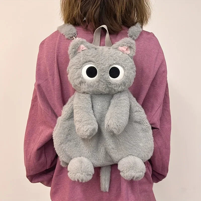 A person wearing KittyNook Cat Co.'s The Cute Big Eyes Plush Backpack over a mauve sweatshirt.