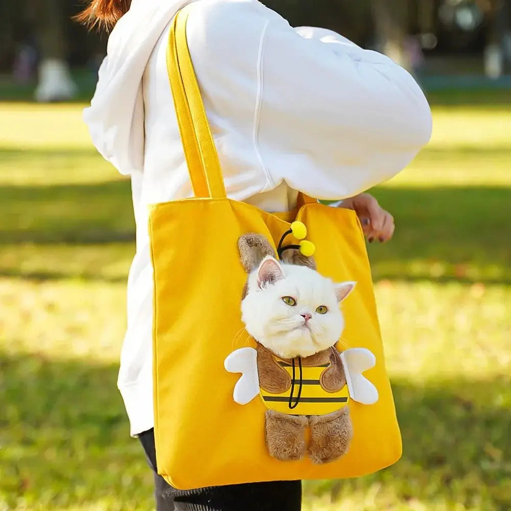Person carrying a yellow KittyNook Cat Co. Portable Crossbody Cat Carrier Bag with a plush bee-dressed cat on front.