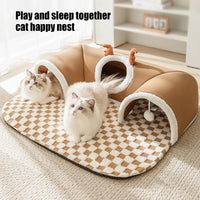 Thumbnail for Two fluffy cats lounge on the KittyNook Cat Co. Winter Warm Plush Tunnel Cat Bed with toys in a cozy, bright room.