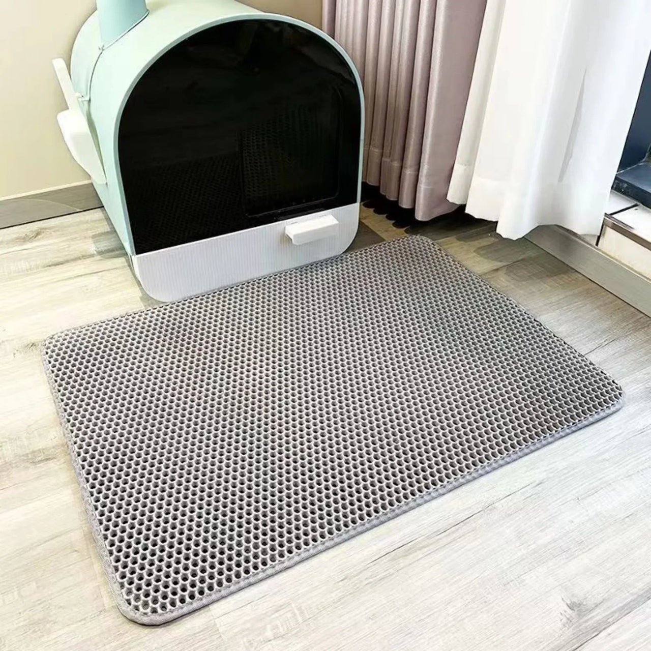 KittyNook Cat Co. Non-Slip Dual Layer Litter Trapper with honeycomb pattern beside a covered litter box on wood floor.