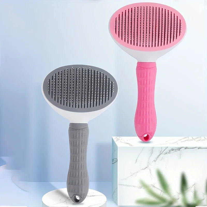 Two KittyNook Cat Co. self-cleaning Pet Grooming Brushes, gray and pink, stand upright on marble with blue backdrop.