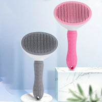 Thumbnail for Two KittyNook Cat Co. self-cleaning Pet Grooming Brushes, gray and pink, stand upright on marble with blue backdrop.