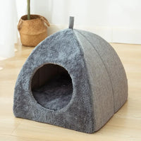 Thumbnail for The KittyNook Cat Co. Cozy Triangle Cat Cave Bed has a plush, tent shape with a circular entrance for cats.