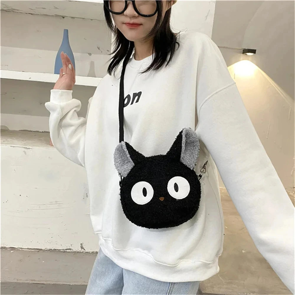 Woman in white sweatshirt and jeans wears the KittyNook Cat Co. Neko Soft Cat Shoulder Bag with anime-style eyes.