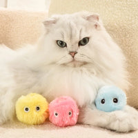 Thumbnail for Fluffy white cat lying next to three KittyNook Cat Co. Interactive Cat Smart Ball Toys in yellow, pink, and blue.
