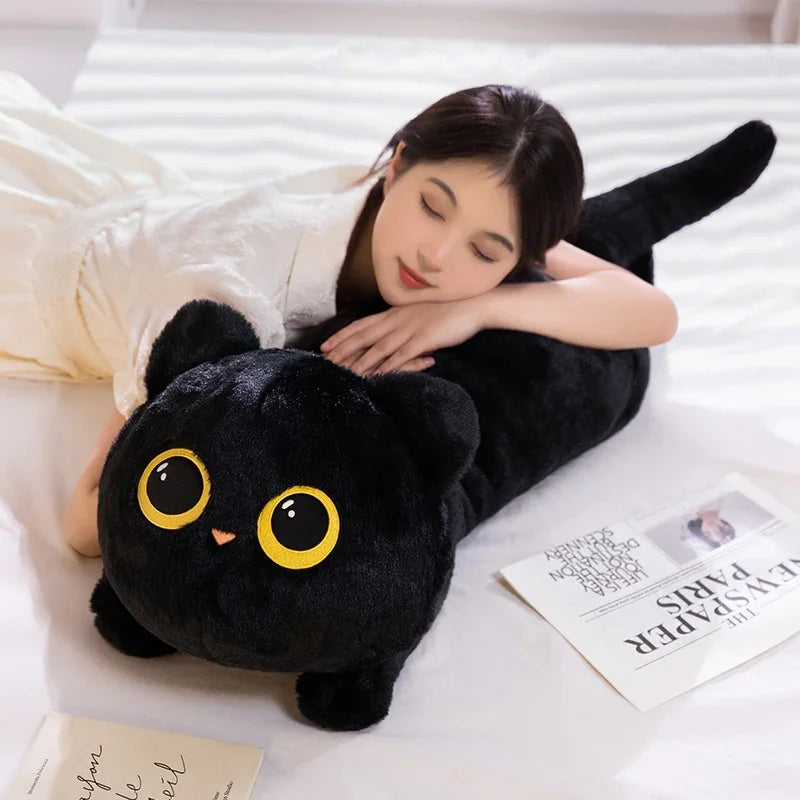 Woman lying on bed hugging KittyNook Cat Co.'s Plush Cat Pillow: Whimsical Home Cozy—ideal cat lover gift, mags nearby.