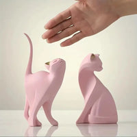 Thumbnail for A hand reaches toward two Golden Couples Cat Figurines by KittyNook Cat Co.—one alert, one calm; perfect for decor.