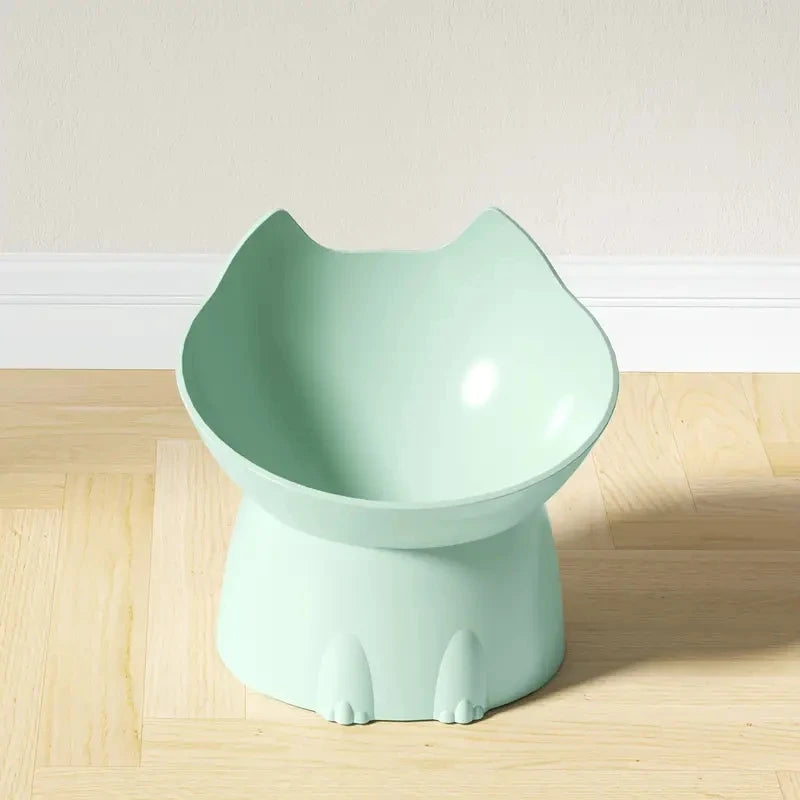 KittyNook Cat Co. Orthopedic Raised Cat Feeder in light green, cat-head shape with paw details, on a wood floor.