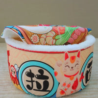 Thumbnail for KittyNook Cat Co. Giant Ramen Bowl Cat Bed features a lucky cat design, Japanese characters, and soft white lining.
