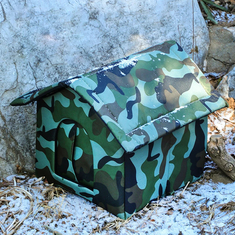 The KittyNook Cat Co. PurrFort Waterproof Outdoor Cat Cave blends into snowy ground with its camouflage design.
