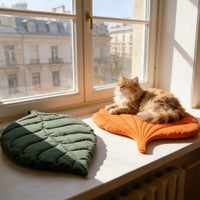 Thumbnail for A long-haired ginger cat naps on an orange, leaf-shaped Leaf Pattern Cat Sleeping Mat next to an identical green one.