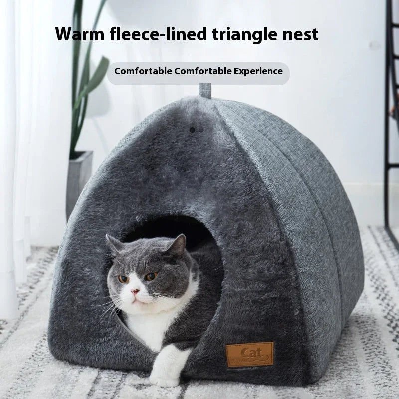 Gray and white cat in the KittyNook Cat Co. Cozy Triangle Cat Cave Bed on a patterned carpet.