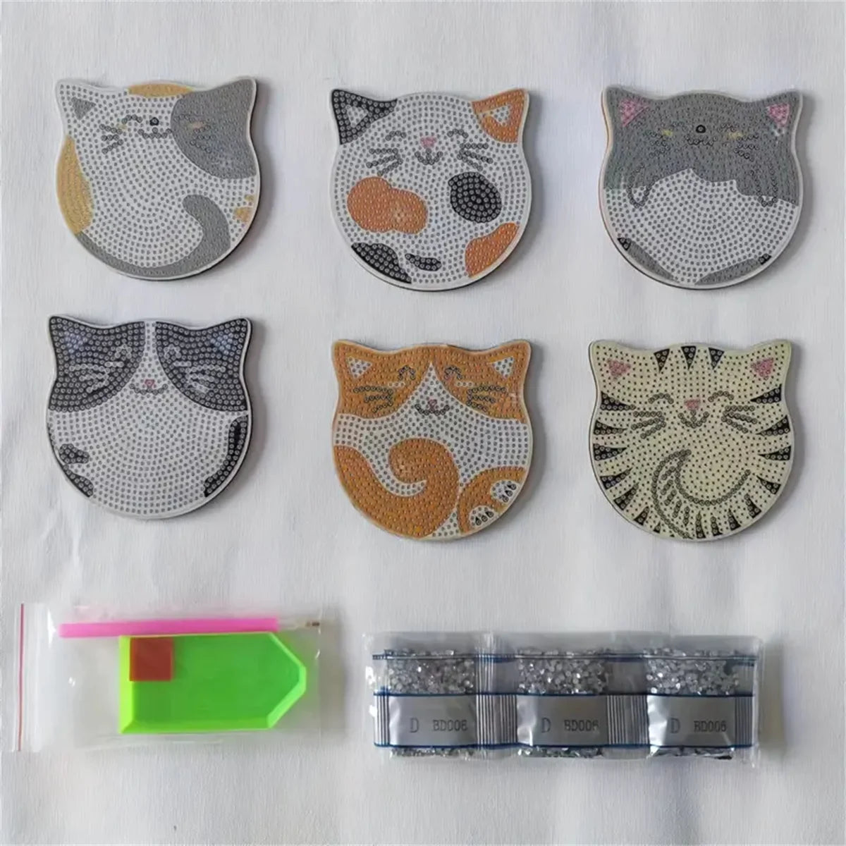 Six DIY Cat Sparkle Mosaic Drink Coasters by KittyNook Cat Co., plus a green tray, pink wax, and diamond beads.