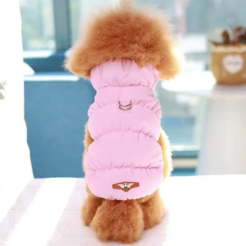 A fluffy brown dog wears the Ultra-Soft Padded Winter Cat Jacket by KittyNook Cat Co., sitting indoors, back to camera.