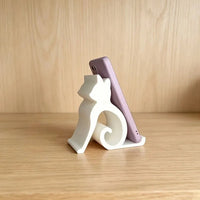 Thumbnail for A Cute Cat Phone Stand – Adjustable Mobile & Tablet Holder shaped like a cat, holding a purple smartphone.