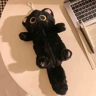 The Kawaii Big-Eyed Cat Plush Pencil Case by KittyNook Cat Co. sits beside a laptop and pencils on a white table.
