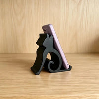 Thumbnail for A Cute Cat Phone Stand – Adjustable Mobile & Tablet Holder holding a smartphone on a wooden surface.