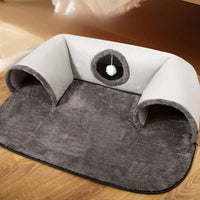 Thumbnail for The KittyNook Cat Co. Interactive U-shaped Cat Tunnel is a soft gray bed with two entrances, center cushion & hanging toy.