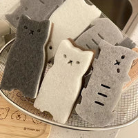 Thumbnail for A drying rack holds KittyNook Cat Co.'s Adorable Cat-Shaped Dish Sponge Set – 4 pieces—in white, gray, and black.