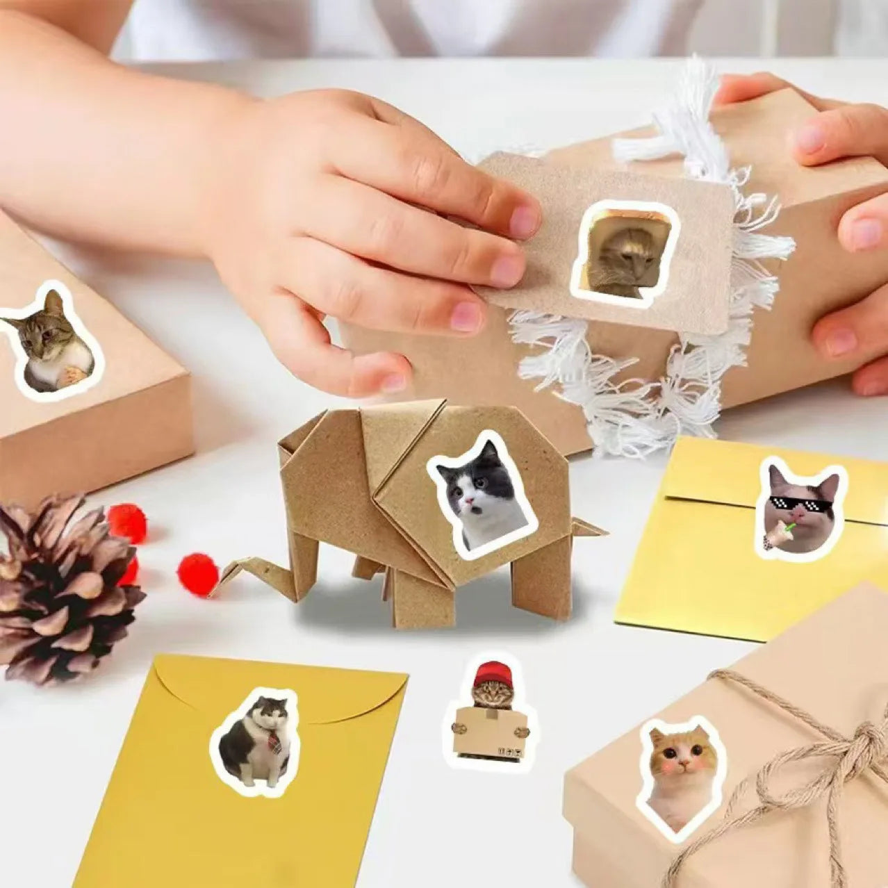 Child decorates gifts with Unique Cute Cat Graffiti Stickers by KittyNook Cat Co., origami elephant, and yellow envelopes.