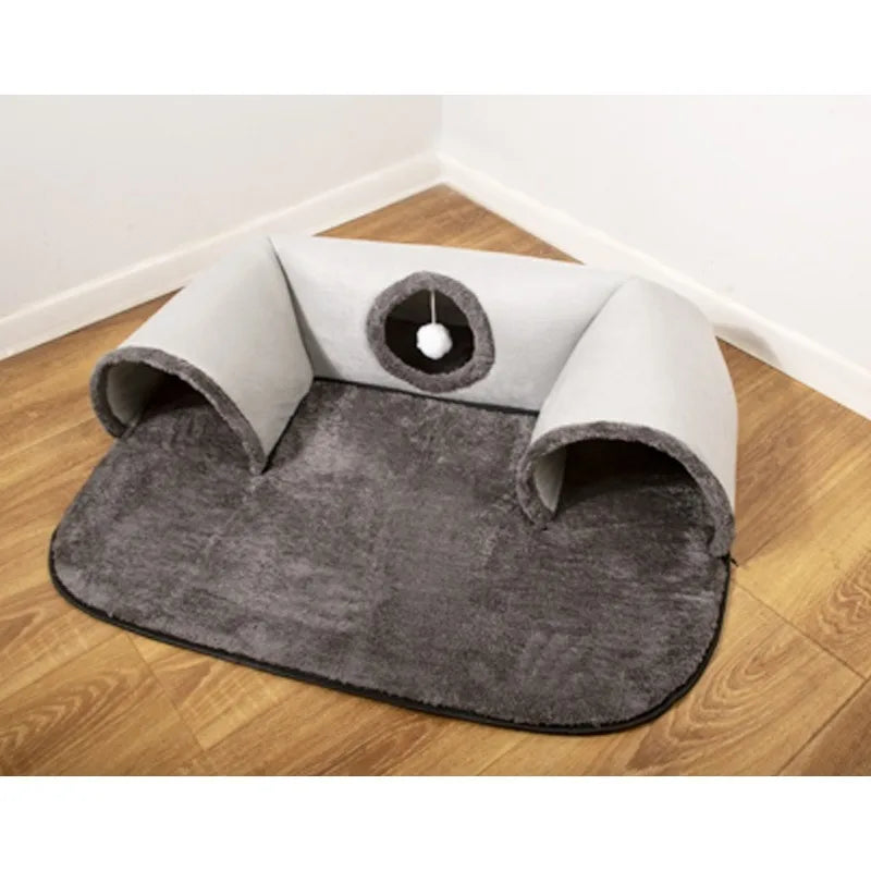 KittyNook Cat Co.’s Interactive U-shaped Cat Tunnel with hanging ball, gray, shown in a corner on wood flooring.