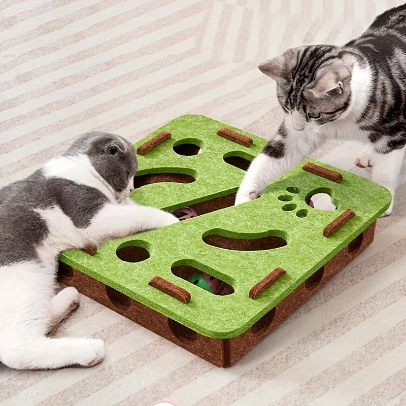 Two cats play with the KittyNook Cat Co. Interactive Felt Cat Maze Puzzle Box, reaching in for toys on a patterned floor.