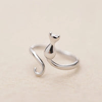 Thumbnail for The Cute Adjustable Silver Cat Ring by KittyNook Cat Co., a minimalist curled tail piece, on a beige background.