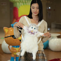 Thumbnail for Woman with a fluffy white cat holds The Purrfect Cat Lover’s Bag by KittyNook Cat Co.; cat statue behind.