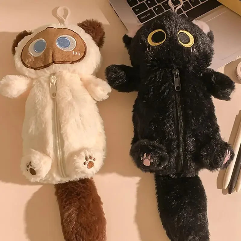Two KittyNook Cat Co. Kawaii Big-Eyed Cat Plush Pencil Cases, one white and one black, sit on a desk by a laptop.