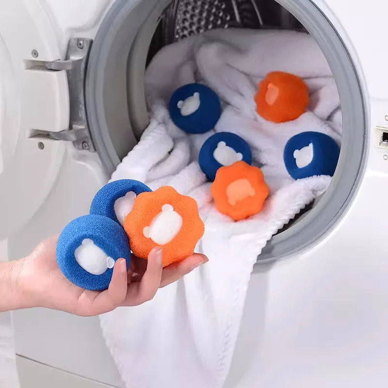 A hand holds The Laundry Pet Hair Filter balls by KittyNook Cat Co. near an open washer with more balls inside.