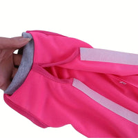 Thumbnail for A hand holds the KittyNook Cat Co. Cat Neutering Recovery Suit in bright pink with grey lining and white Velcro strips.